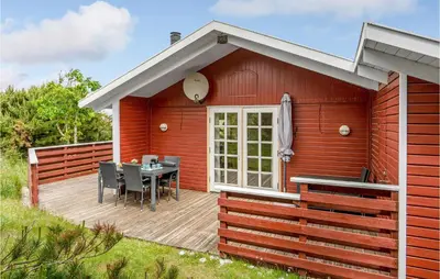 a red house with a table on a deck at Holiday Home Svenstibakkevej Denmark Ii in Frøstrup