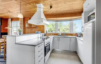 a kitchen with white cabinets and a wooden ceiling at Holiday Home Svenstibakkevej Denmark Ii in Frøstrup
