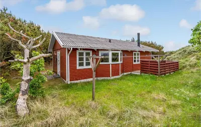 a red cabin in the middle of a grass field at Holiday Home Svenstibakkevej Denmark Ii in Frøstrup