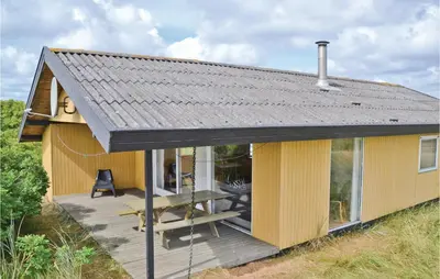 a small yellow house with a wooden deck at Holiday Home Svenstibakkevej Frøstrup Xii in Frøstrup