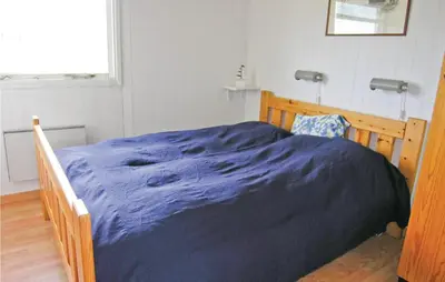 a bedroom with a wooden bed with a blue blanket at Holiday Home Svenstibakkevej Frøstrup Xii in Frøstrup