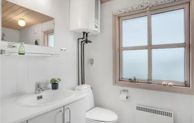 a bathroom with a toilet and a sink and a window at Holiday Home Svenstibakkevej Denmark in Frøstrup