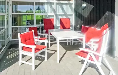 a patio with red chairs and a white table at Holiday Home Aspevej Fjerritslev Xi in Fjerritslev