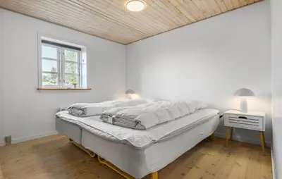 a white bedroom with a bed and a window at Holiday Home Strandvejen Brovst Denm in Brovst