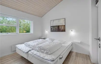 a white bedroom with a bed and a window at Holiday Home Kronvildtvej Brovst I in Brovst