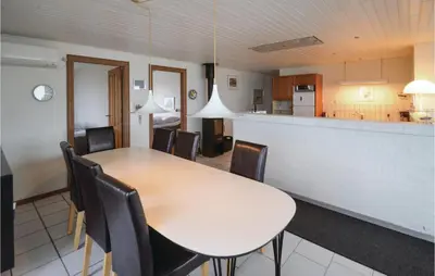 a dining room with a table and chairs and a kitchen at Holiday Home Sandnæshagevej Frøstrup Iv in Frøstrup