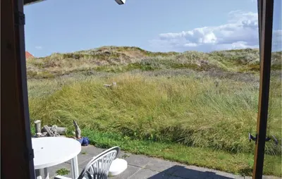 a patio with a table and chairs and a field of grass at Holiday Home Svenstibakkevej Frøstrup in Frøstrup
