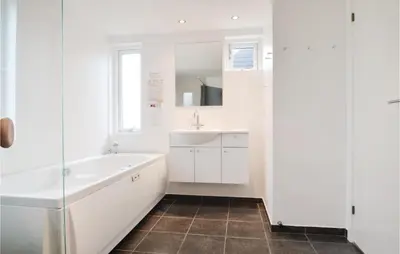 a bathroom with a tub and a sink at Holiday Home Kronvildtvej Brovst in Brovst