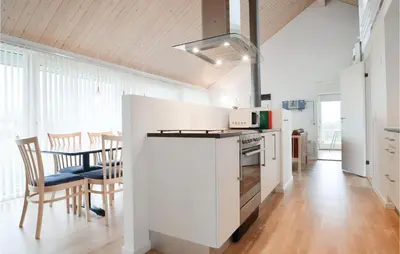 a white kitchen with a table and chairs in it at Holiday Home Kronvildtvej Brovst in Brovst