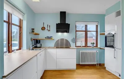 a kitchen with white cabinets and blue walls at Holiday Home Strandvejen Harboøre X in Harboør