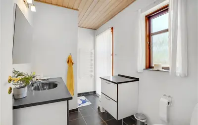 a small bathroom with a sink and a window at Holiday Home Strandvejen Harboøre X in Harboør
