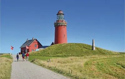 a lighthouse on a hill next to a house at Holiday Home Strandvejen Harboøre X in Harboør