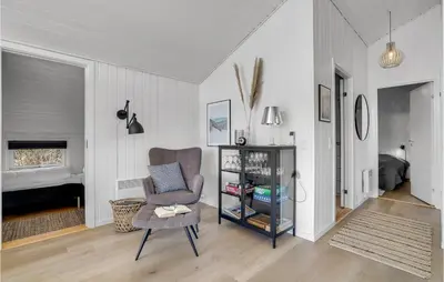 a living room with a chair and a bedroom at Holiday Home Hermodsvej Harboøre Xi in Harboør