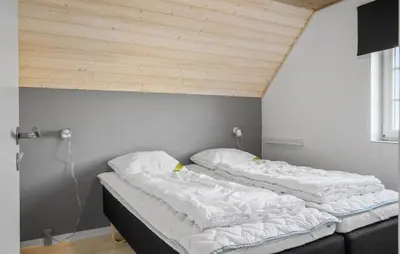 two unmade beds in a room with a wooden ceiling at Gorgeous Home In Harboøre With Sauna in Harboør