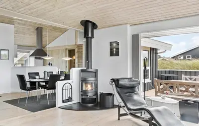 a fireplace in a living room with a table and chairs at Holiday Home Monasvej Løkken Iv in Løkken