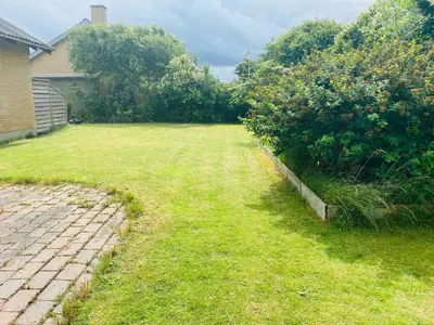 a yard with a grass field and a house at Beautiful villa close to beach and nature in Hanstholm