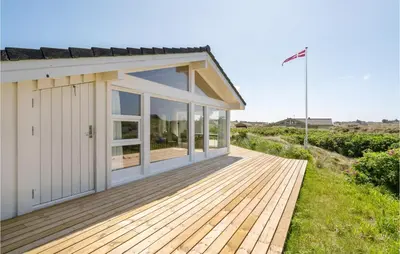 a house with a wooden deck next to a building at Holiday Home Monasvej Xii in Løkken