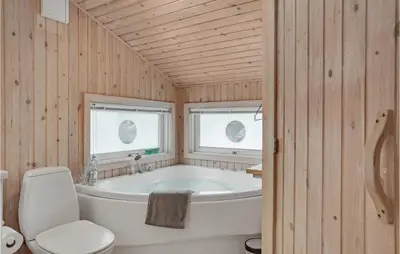 a bathroom with a white tub and a toilet at Holiday Home Monasvej Xii in Løkken