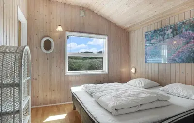 a bedroom with a bed in a room with a window at Pynten in Løkken