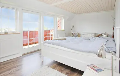 a white bedroom with a bed and windows at Holiday Home Rødhus Klitvej in Pandrup