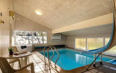 a swimming pool in a house with a table and a chair at 4 Bedroom Awesome Home In Saltum in Saltum