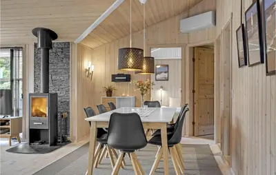 a dining room with a table and chairs and a fireplace at Holiday Home Jægerens Vej in Blokhus