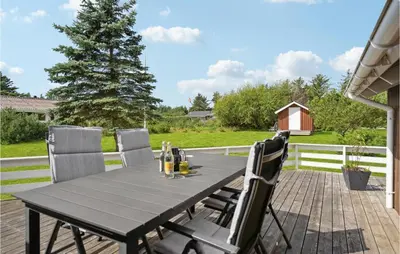 a table and chairs on a patio with a fence at Holiday Home Kristavej Løkken Xii in Løkken
