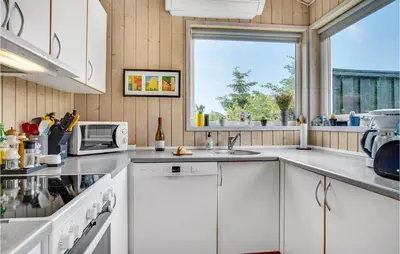 a kitchen with white cabinets and a window at Holiday Home Stellavej Løkken Denm in Løkken