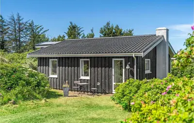 a black shed with white windows on a yard at Holiday Home Lyngvej Blokhus Iv in Blokhus