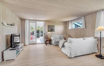 a living room with a white couch and a tv at Holiday Home Lyngvej Blokhus Iv in Blokhus