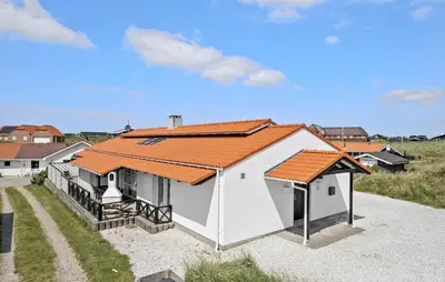 a white house with an orange roof on a beach at Stunning Home In Blokhus With Sauna in Blokhus