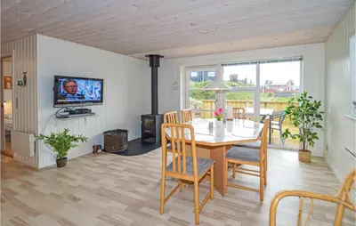 a dining room with a table and chairs and a tv at Holiday Home Kristinesvej Blokhus X in Blokhus