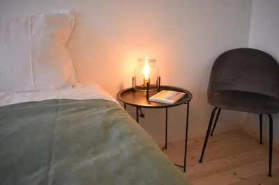a table with a candle and a chair next to a bed at Viking Surf House in Klitmøller