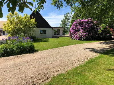 a house with purple flowers and a gravel driveway at Landevejens B&B Holstebro in Holstebro