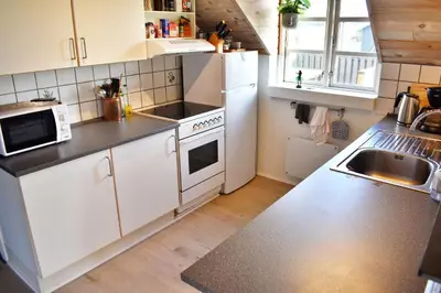 a kitchen with white appliances and a sink at Viking Surf Cottage in Klitmøller