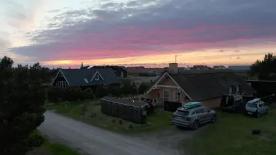 a truck parked in front of a house with a sunset at Viking Surf Cottage in Klitmøller