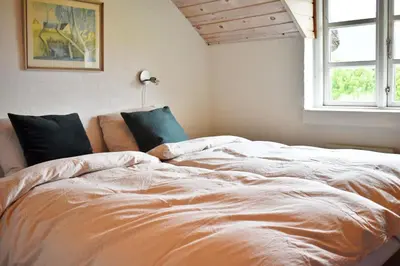 a large bed in a room with a window at Viking Surf Cottage in Klitmøller