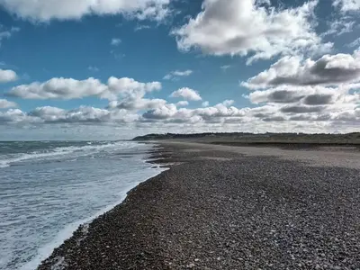 a beach with a cloudy sky and the ocean at 6 person holiday home in Brovst-By Traum in Brovst