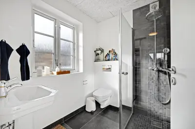 a bathroom with a shower and a toilet and a sink at Lildgaard in Frøstrup