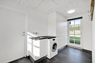 a laundry room with a washing machine and a window at Lildgaard in Frøstrup