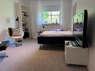 a bedroom with a bed and a mirror and a chair at Kørestolsvenligt dbl. vær. in Nykøbing Mors