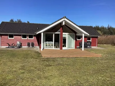 a red house with a deck in front of it at 8 person holiday home in Brovst-By Traum in Brovst