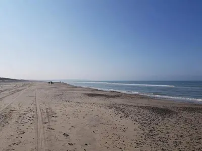 a beach with people walking on the sand and the ocean at 6 person holiday home in Brovst-By Traum in Brovst