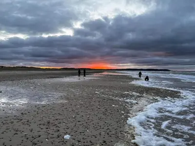 a group of people walking on the beach at sunset at 6 person holiday home in Brovst-By Traum in Brovst