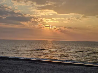 a sunset over the ocean on a beach at 12 person holiday home in Thisted-By Traum in Thisted