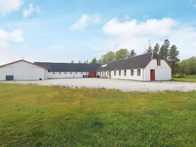 a large white barn with a red door on a field at 12 person holiday home in Thisted-By Traum in Thisted