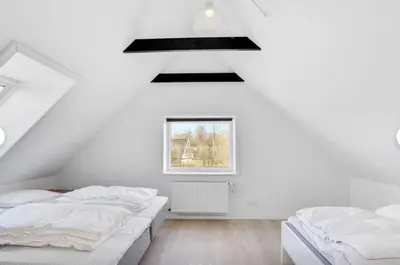 two beds in a white room with a window at Lundø in Højslev
