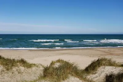 a sandy beach with the ocean in the background at Stone Mountain BnB in Stenbjerg