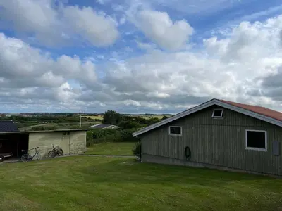 a house with a bike parked in a yard at Ældre Sommerhus Max 4 voksne og 4 børn in Lemvig