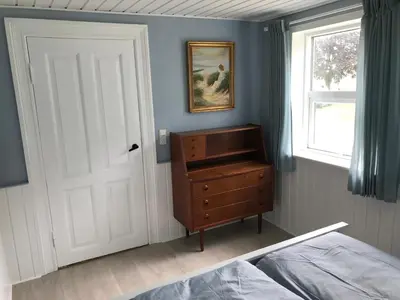 a bedroom with a door and a dresser and a window at Sommerhus på Mors in Øster Assels